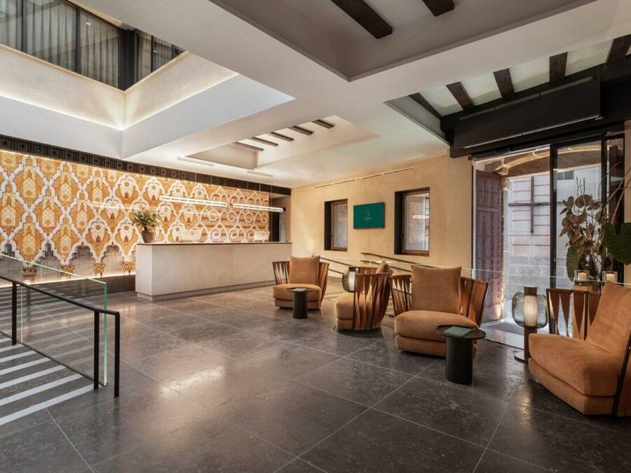 A spacious lobby with a high ceiling, a patterned wall, and a seating area with sofas and chairs.