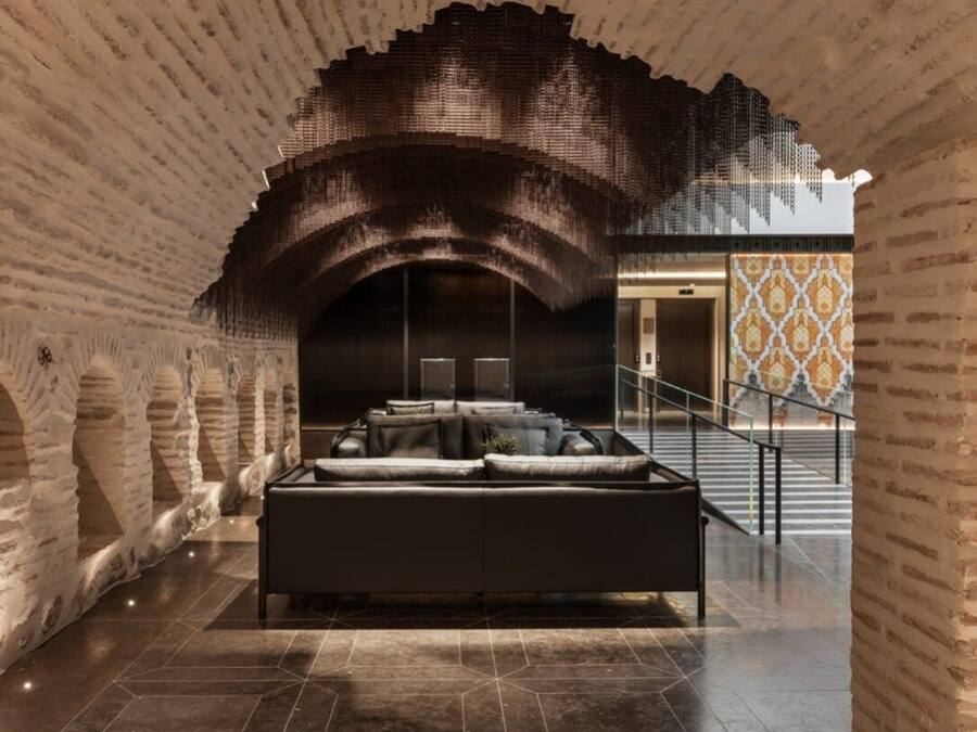 Een interieur met een centraal zitgedeelte, een trap en bakstenen muren.