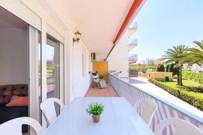En balkon med et hvidt bord, stole og en potteplante.
