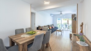 A modern dining area with a wooden table, grey chairs, and a sofa in the background. - ADRIAN Apartment (La Pineda)