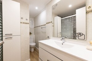 Et moderne badeværelse med en hvid vask, et spejl og et toilet.