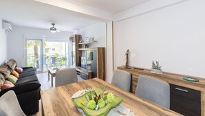 A modern living room with a wooden dining table, a sofa, and a balcony with a view. - ADRIAN Apartment (La Pineda)