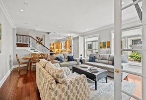 Relax in this inviting living area with a large sofa, dining table, and staircase leading to an upper level.