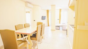 Habitación de hotel con zona de comedor que incluye una mesa, sillas, televisión y una cama.
