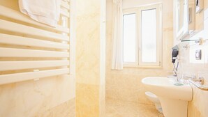 Un baño con una bañera blanca, un lavabo y una ventana con cortinas.
