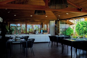 Un comedor moderno con vigas de madera en el techo, ventanas amplias y vistas a zonas verdes.