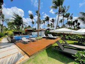 A pool area with wooden decking, lounge chairs, and umbrellas.