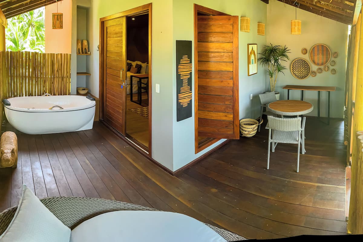 A wooden deck with a hot tub, wicker furniture, and a dining area with a table and chairs.