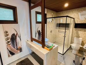 A modern bathroom with a glass shower enclosure, a marble sink, and a toilet.