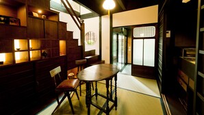 A traditional Japanese room with tatami flooring, a low wooden table, a cushioned chair, and built-in wooden shelves. - Tikkan Tsuyukusa-An (Kyoto)
