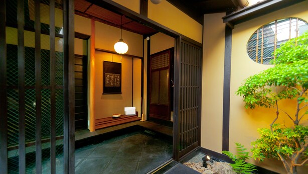 A traditional Japanese interior with tatami flooring, a shoji screen door, and a small garden area with a tree and rocks. - Tikkan Tsuyukusa-An (Kyoto)