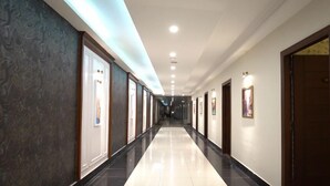 A long, well-lit hallway with doors on both sides, leading to rooms. - Hotel Heaven Heights (Islamabad)