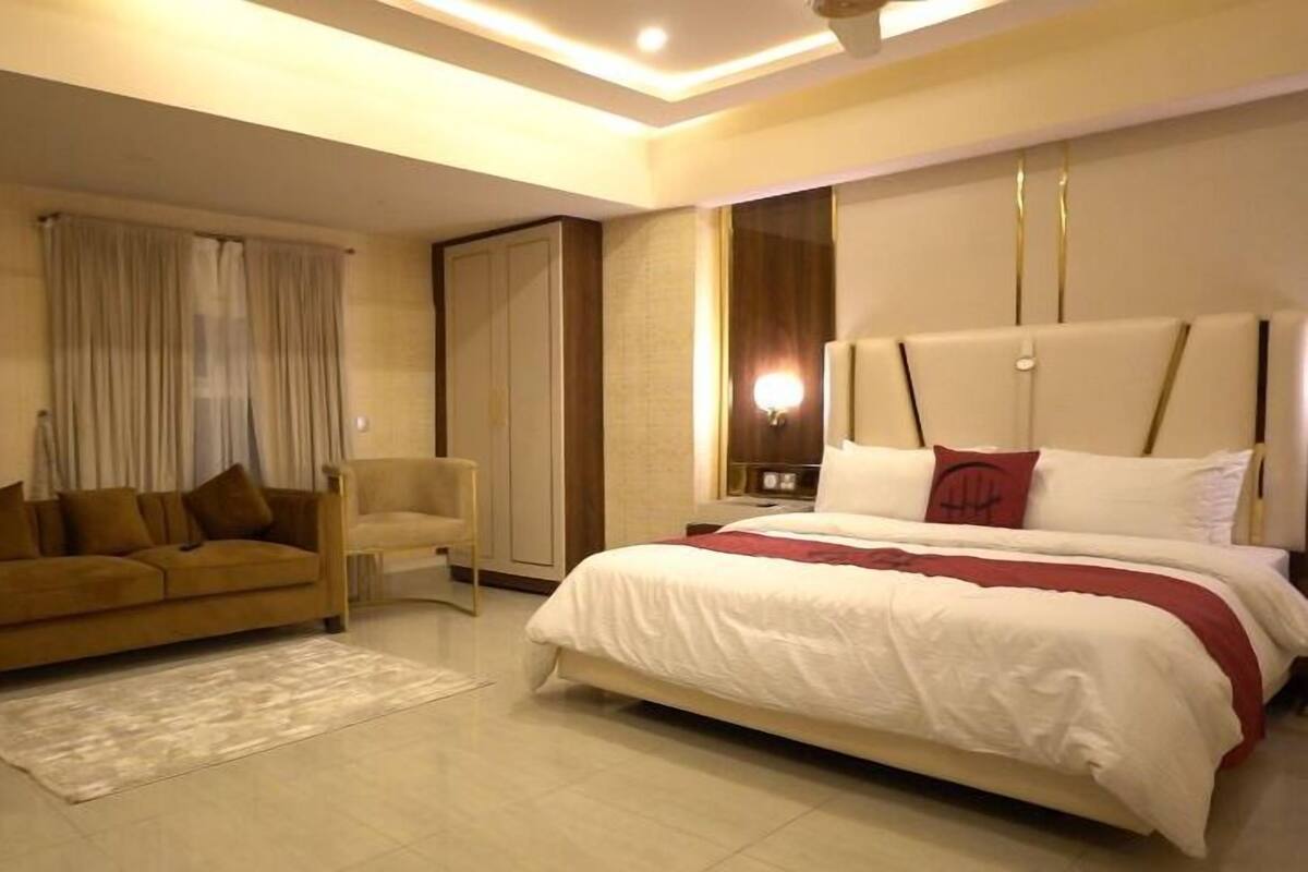 A modern hotel room with a large bed, a sofa, and a desk.