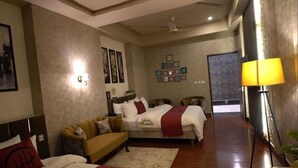 A hotel room with a bed, a sofa, a desk, and a lamp. - Hotel Heaven Heights (Islamabad)