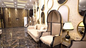 A reception area with a marble floor, a sofa, armchairs, and a wall with circular mirrors. - Hotel Heaven Heights (Islamabad)