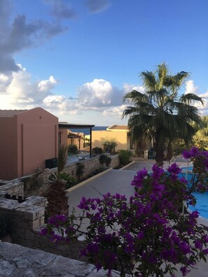 A resort with a pool, palm trees, and a clear sky.