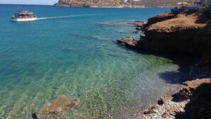 A coastal scene with clear water, a boat, rocky shore, and a distant hill. - Nina's Place, 5min On Foot From The Beach (Mylopotamos)