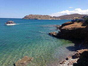 A coastal scene with clear water, a boat, rocky shore, and a distant hill. - Nina's Place, 5min On Foot From The Beach (Mylopotamos)