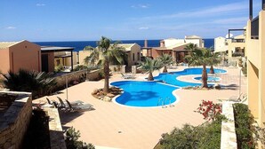 A resort with a pool area, palm trees, and a view of the sea. - Nina's Place, 5min On Foot From The Beach (Mylopotamos)