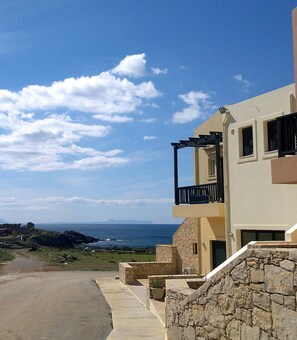 A coastal building with a balcony, stone walls, and a view of the sea.