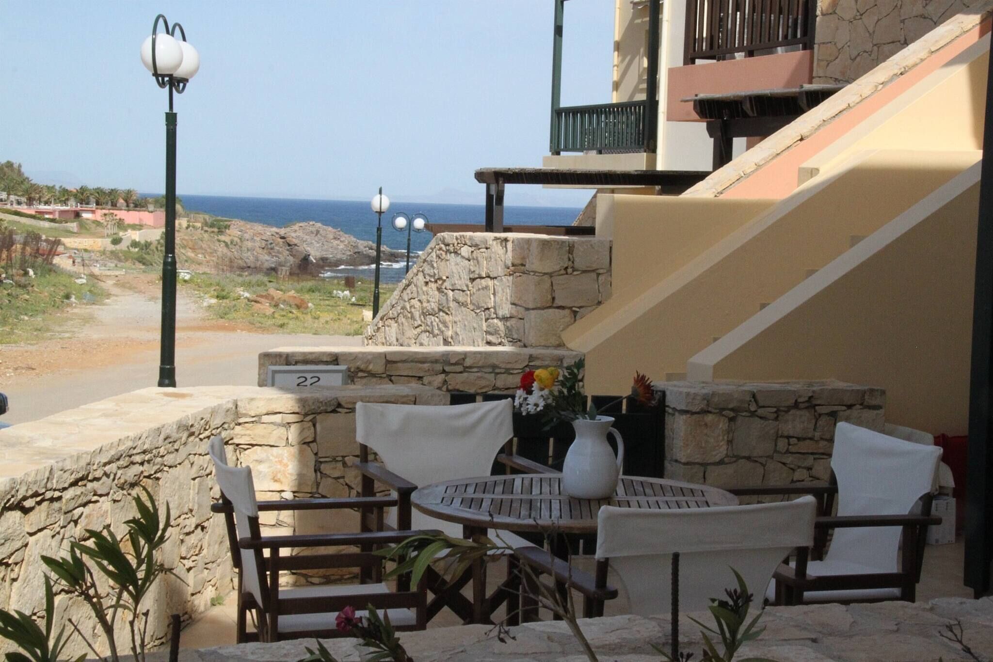 Une terrasse aux murs de pierre, avec une table et des chaises, d’où l’on peut admirer un paysage côtier.