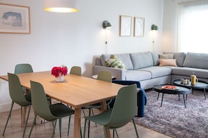 A modern living room with a wooden dining table, green chairs, a grey sofa, and a coffee table with a tray. - Cabot Views by Revelstoke Vacations (Revelstoke)