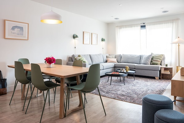 A modern living room with a sofa, dining table, chairs, and a coffee table. - Cabot Views by Revelstoke Vacations (Revelstoke)