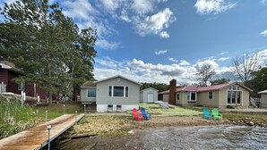 Une propriété située au bord de l’eau, dotée d’un quai, d’une pelouse avec des chaises et de plusieurs petites maisons.