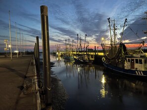 Ein Yachthafen im Abenddämmerung mit vertäuten Booten, ruhigem Wasser und Laternen entlang des Stegs.