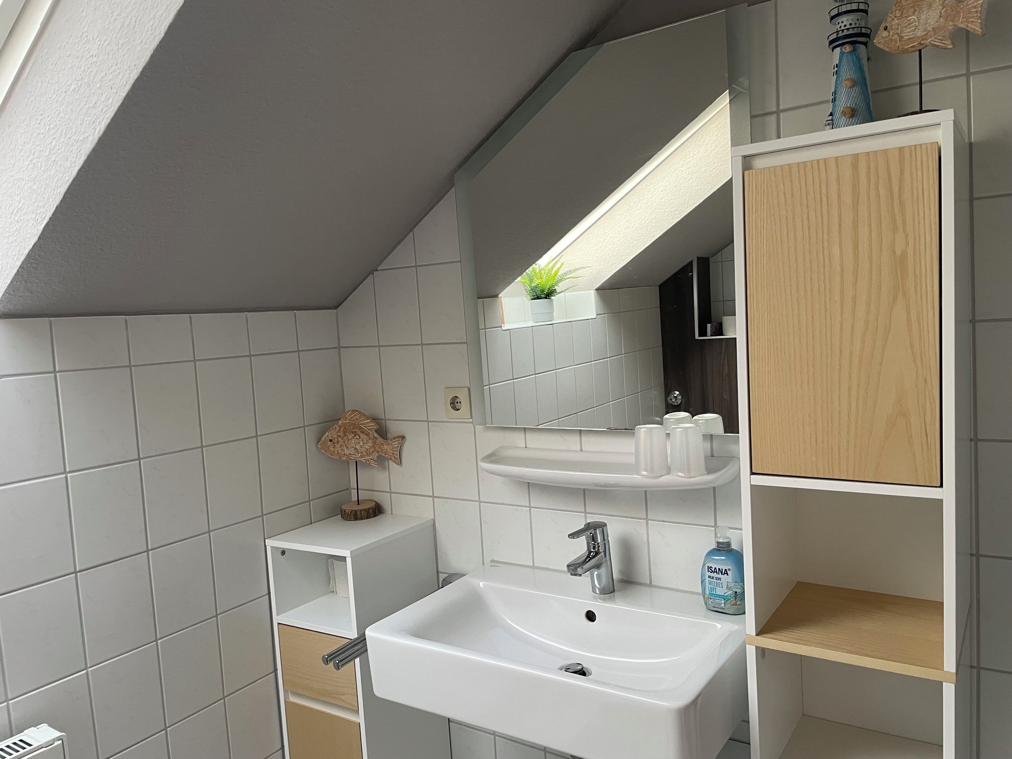 Ein modernes Badezimmer mit Waschbecken, Spiegel und Regalen.