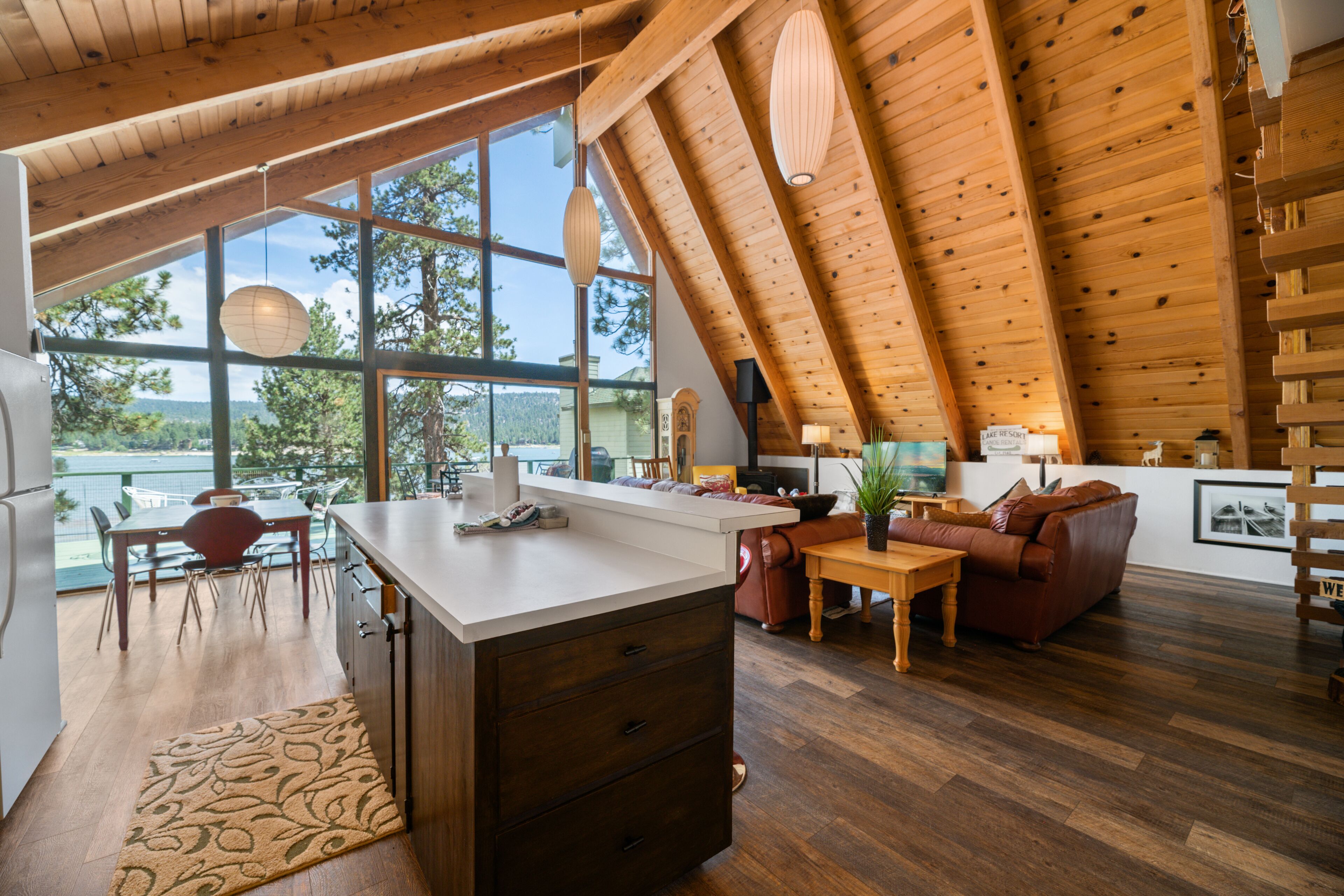 Una cocina amplia con una isla grande, techo de madera y ventanas grandes que ofrecen vistas al exterior.