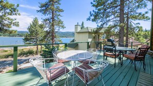 A deck with a table and chairs, overlooking a lake and surrounded by trees. - Moonlight Shores Lakefront (Fawnskin)