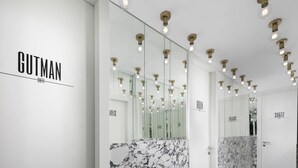 Een moderne hotelgang met marmeren vloer, spiegelwanden en inbouwspots.