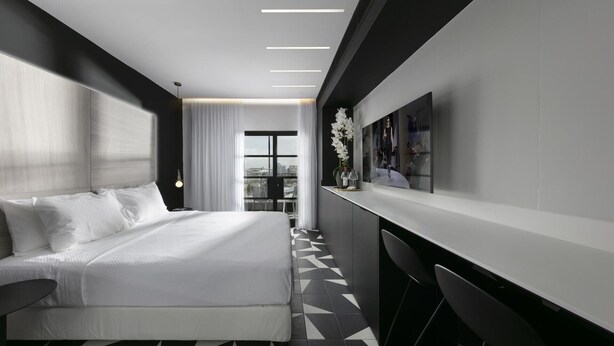 Een moderne hotelkamer met een groot bed, een bureau en uitzicht op de stad.