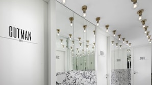 En modern hotellkorridor med marmorgolv, spegelväggar och taklampor.
