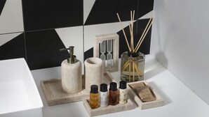 En badrumsmöbel med en tvålpump, en glasflaska med doftstickor och flera små flaskor med flytande tvål.