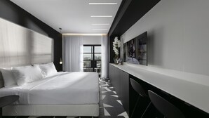 Une chambre d’hôtel moderne, dotée d’un grand lit, d’un bureau et offrant une vue sur la ville.