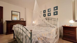 Una camera da letto con un letto a baldacchino, un comò, un comodino con una lampada e uno specchio a parete.