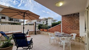 Un espace patio aménagé avec une table et des chaises, un grand parasol et une plante en pot.