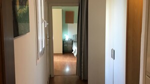 Un couloir au plancher de bois menant à une cuisine.