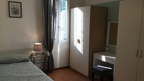 Une chambre à coucher comprenant un lit, un bureau, une chaise, une lampe et une armoire.