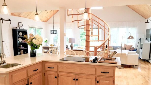 Una cocina moderna con armarios de madera, una isla central e iluminación colgante.