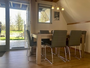 Un coin repas avec une table en bois et quatre chaises, une fenêtre donnant sur l’extérieur et un luminaire au plafond.