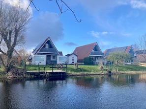 Une propriété située au bord du lac, dotée d’un quai, d’une maison avec balcon et d’un bâtiment voisin.