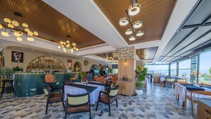A modern restaurant with a bar area, dining tables, and chairs. - Ornella Hotel (Edremit)