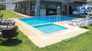 A two-story building with a swimming pool, outdoor seating, and a mountain backdrop. - Ornella Hotel (Edremit)