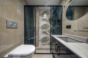 Un baño moderno con inodoro, cabina de ducha con puertas de vidrio y tocador con espejo.