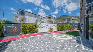A hotel entrance with a paved area, a red carpet, and a signboard. - Ornella Hotel (Edremit)