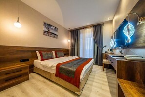 A modern hotel room with a large bed, bedside table, and a flat-screen TV. - Ornella Hotel (Edremit)