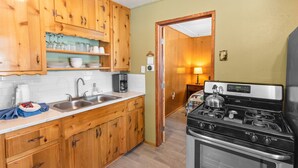 Una cocina compacta con armarios de madera, un lavamanos de acero inoxidable y una estufa negra.